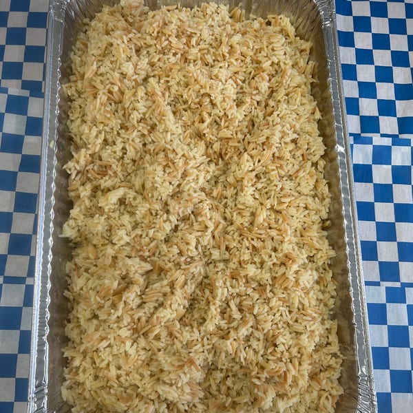 A large aluminum tray filled with fluffy rice pilaf, featuring both white rice and golden vermicelli.
