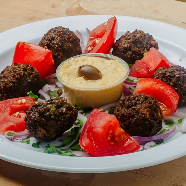 Little Greece falafel appetizer with hummus, tomatoes, red onion, and parsley on a white plate.